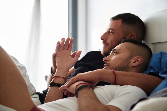 Smiling gay couple hugging on bed