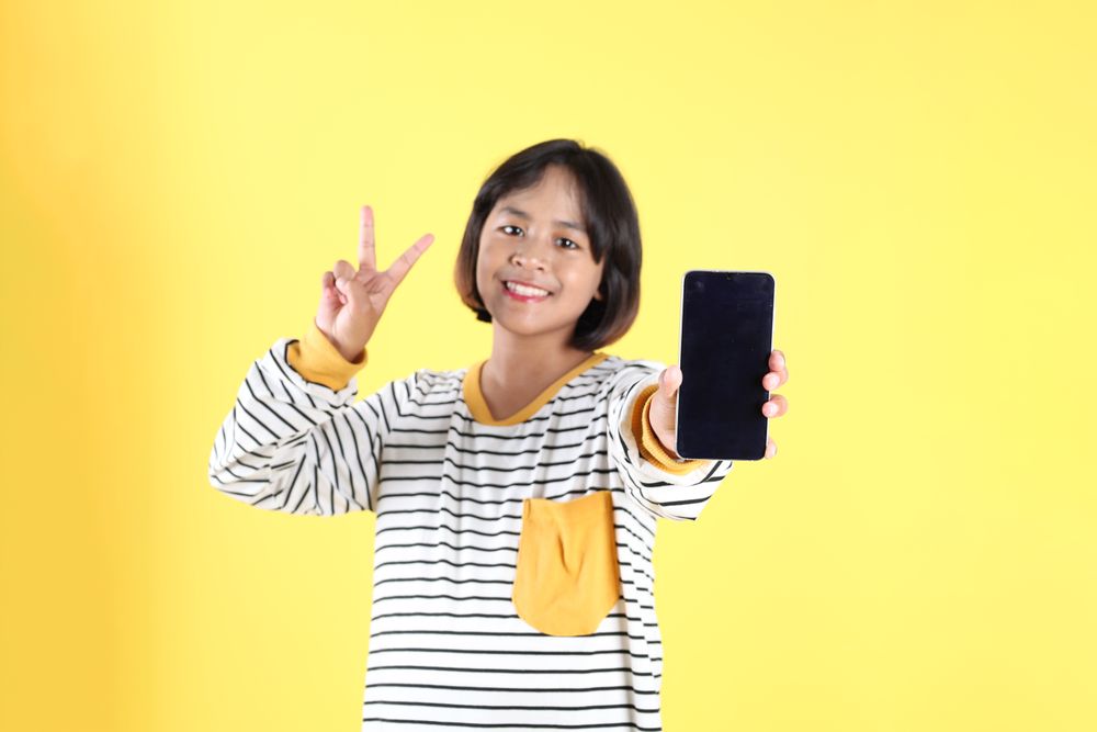 Indonesian Girl Kids Making Peace Sign Holding Mobile Phone