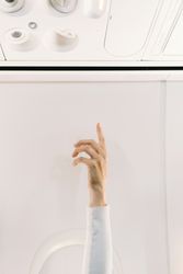 Person in white sweater raising hand up in plane
