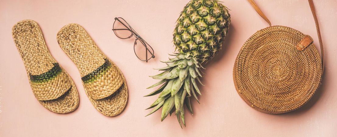 Sandals, glasses, pineapple, bag on pink background, wide composition