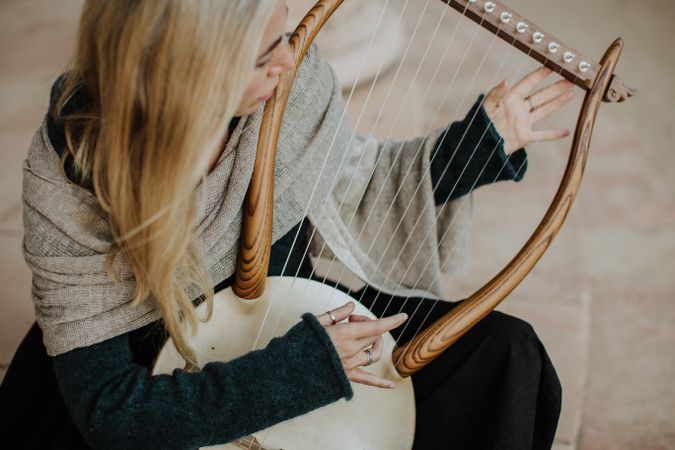 Romantic female musician playing lyre in terrace
