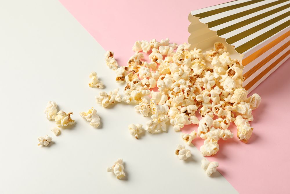 Composition with striped box and popcorn on color background