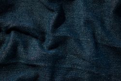 Close up detail crumpled wavy Navy blue jeans fabric background texture.