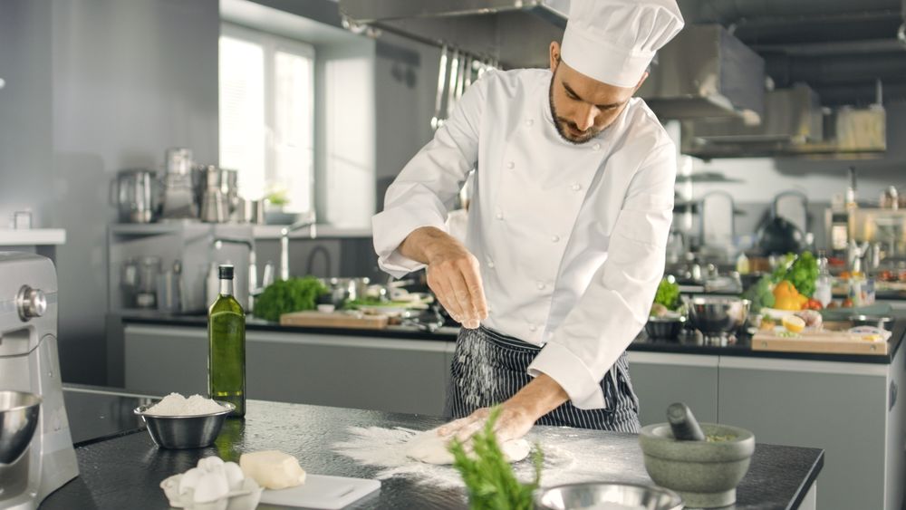 Baker Chef of Famous Restaurant Kneads the Dough in a Modern Looking Kitchen.
