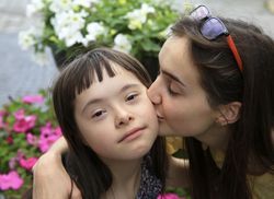 Older sister giving young child a kiss on her cheek