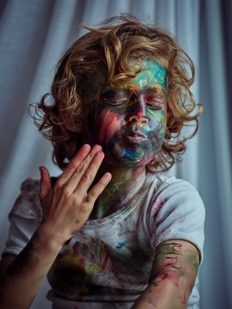 Dirty boy smearing paint on face