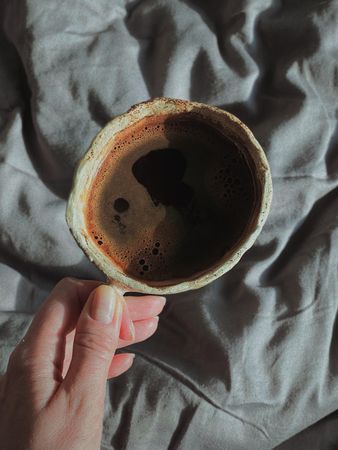 Female hand holding ceramic cup with coffee