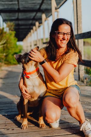 Happy adult woman hugging dog at countryside