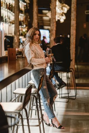 Stylish woman drinking wine in bar