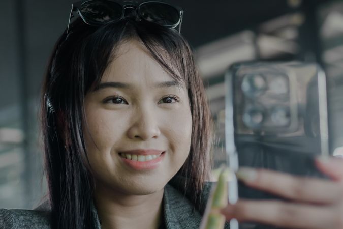 Cheerful Asian Woman Engaged in Smartphone Activity, Smiling Wid