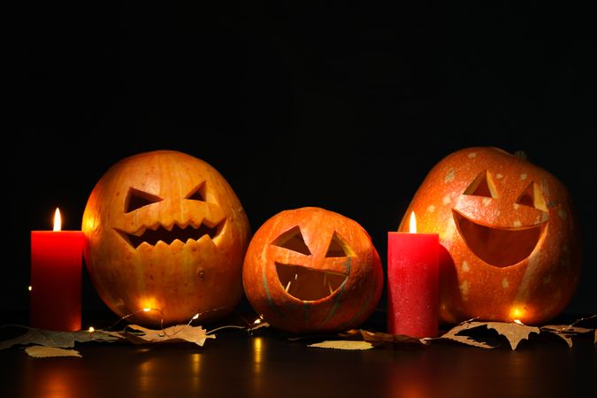 Halloween pumpkins and candles on dark background, copy space