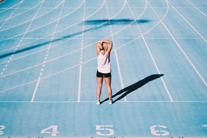 Young woman doing an upper body stretch on a track field