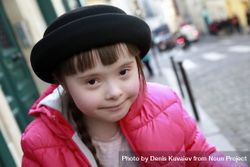 Beautiful little girl with Down syndrome wearing a pink puffer coat and hat smiling 5q3Lqb