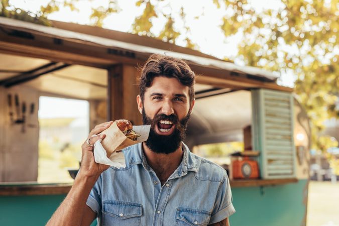 Young guy with beard holding a cheeseburger