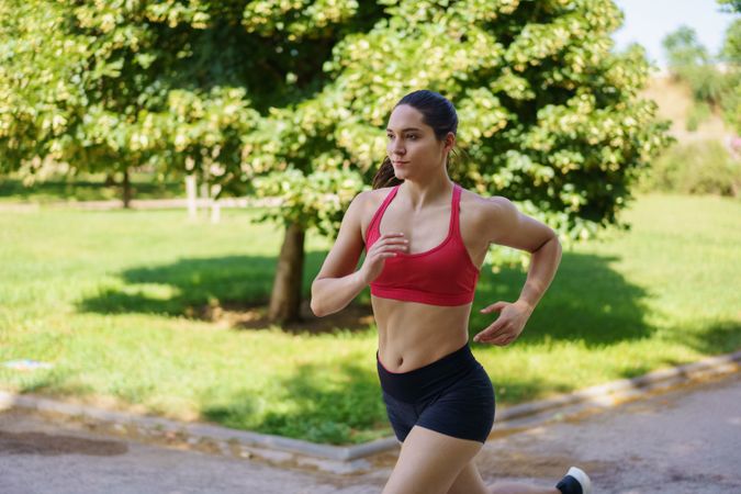 A young woman is running outdoors in a park, dedicated to fitness and maintaining a healthy lifestyle