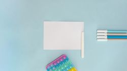 Flat lay of pens and paper on blue background