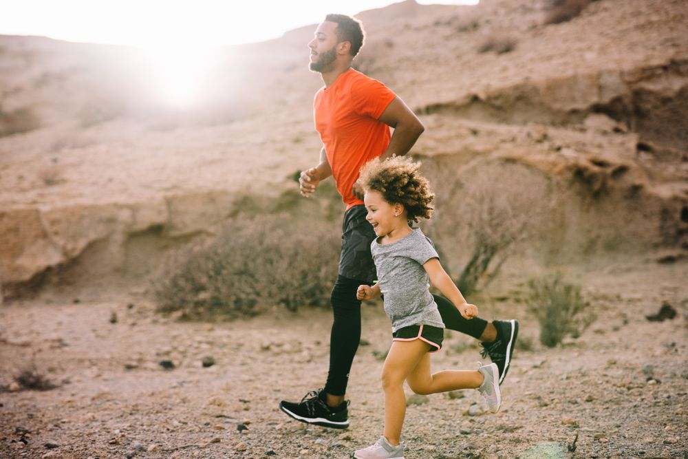 Black man jogging with toddler on nature