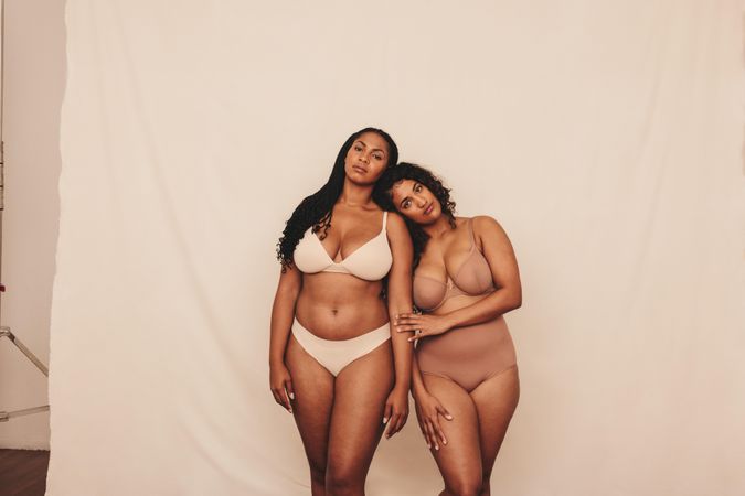 Two body positive young women wearing underwear in a studio