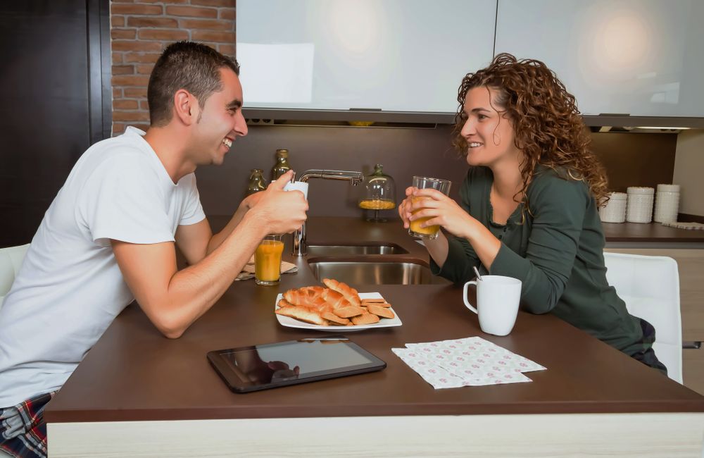 Smiling couple chatting over breakfast of pastries and coffee