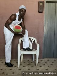 Young man holding watermelon putting one leg on plastic chair 5pyny4
