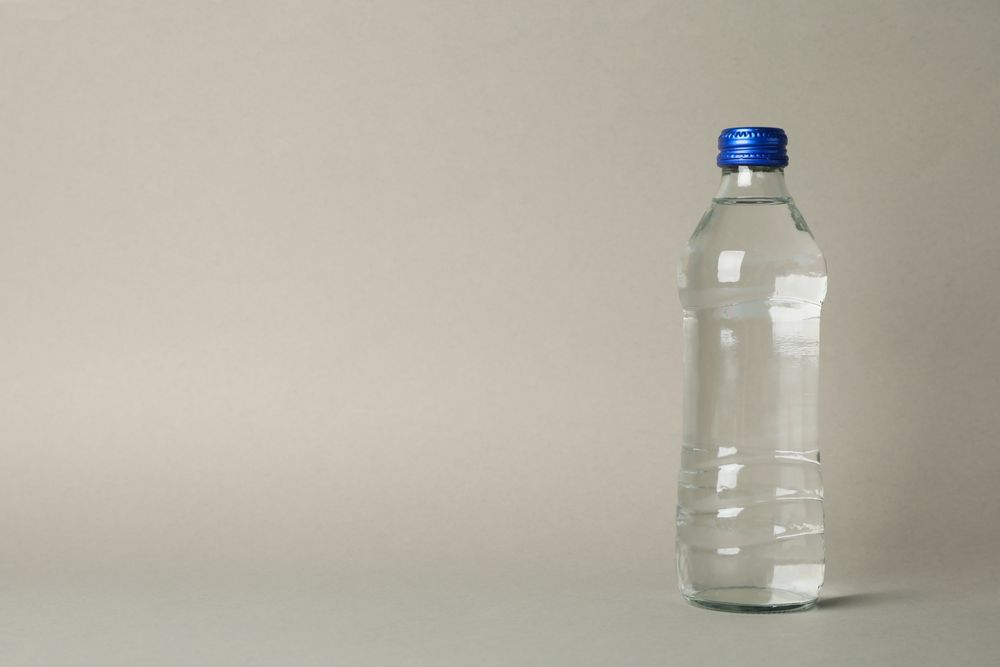 Plastic water bottle in beige room with copy space