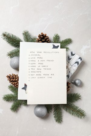 Paper with list and decorations on light background, top view