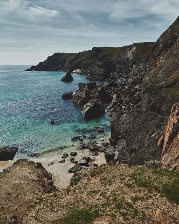 Rocky cliffs in Cornwall looking down to the sea with cloudy sky