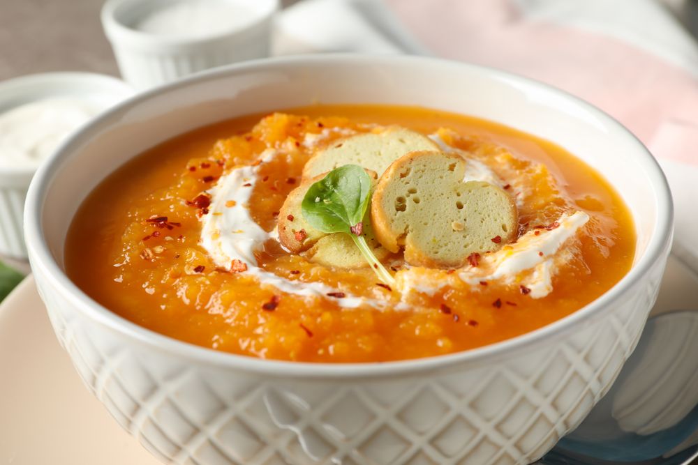 Pumpkin soup with creme and garnish in bowl on table