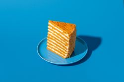 Slice of medovik, honey layered cake, isolated on a blue background