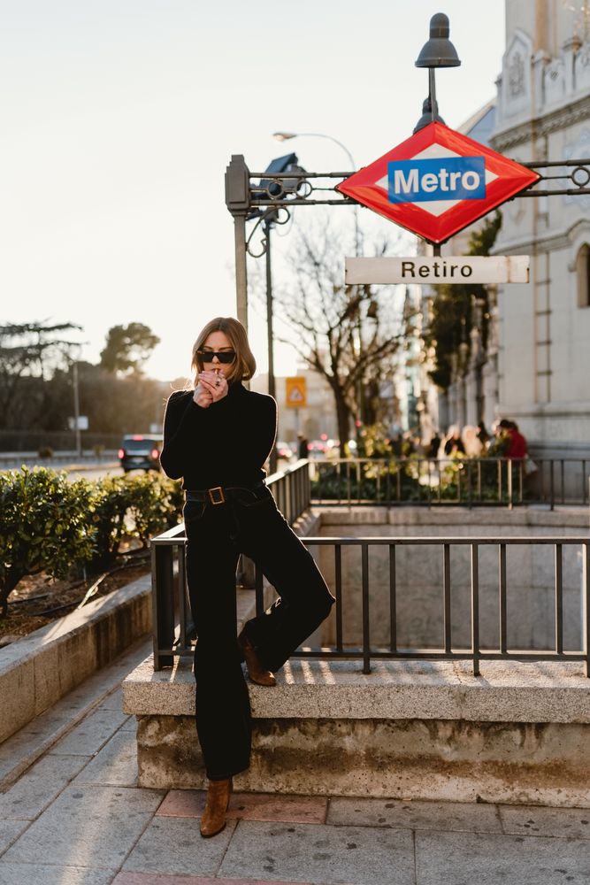 Stylish woman lighting cigarette near metro station