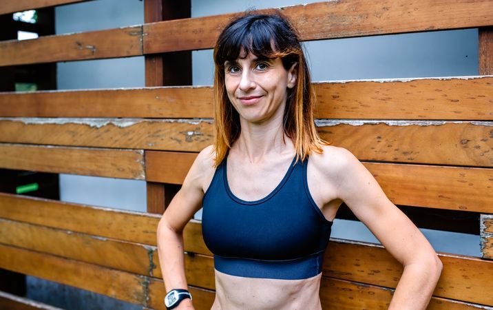 Cheerful female athlete in front of a wooden background