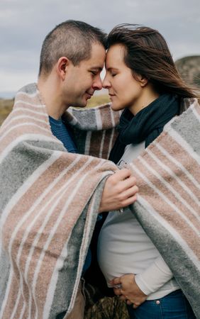 Pregnant woman with husband covered with a blanket