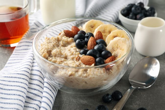 Composition with oatmeal porridge with fruits on gray background