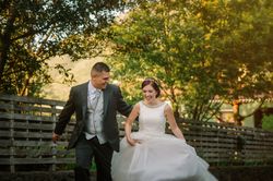 Happy just married couple running along fence in garden