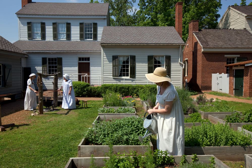 Women in historic period costume in backyard garden of old home in Alabama