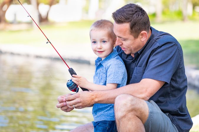 Young White Father and Son Having Fun Fishing At The Lake