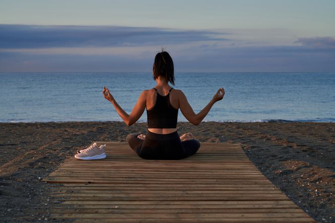 Unrecognizable woman meditating near sea