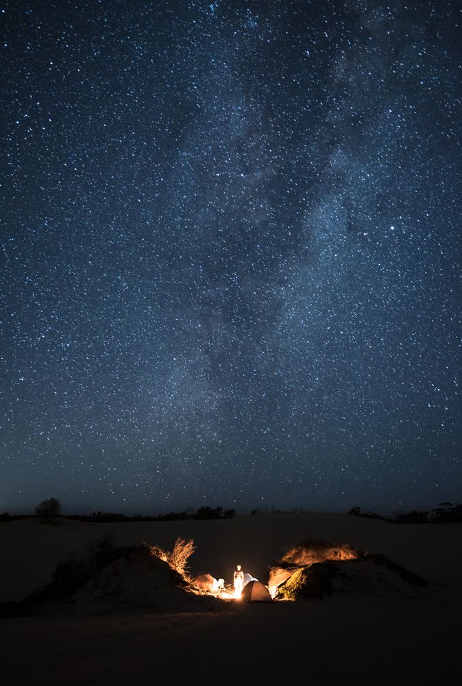 Bonfire surrounded by tents during starry night