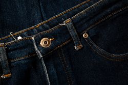 Close up gold and shiny button navy blue jeans fabric background texture.
