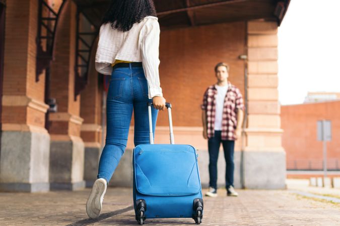 Young couple meeting outside the train station after a trip