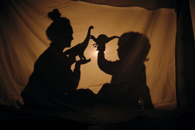 Silhouette of woman and boy playing in shadow theater