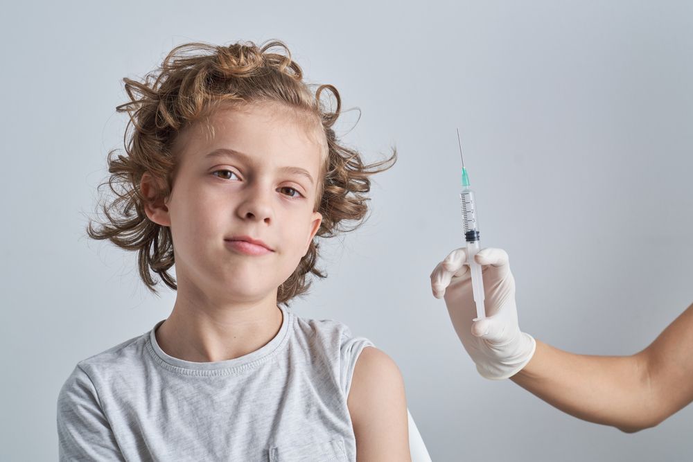 Calm kid with nurse showing syringe