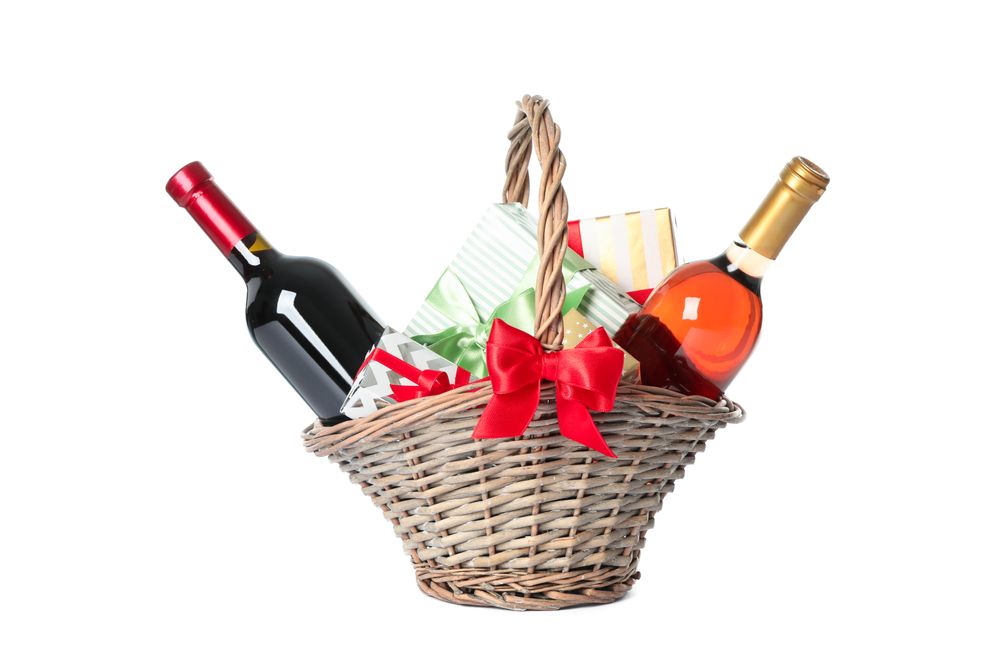 Wicker basket with bottles of wine and presents isolated on plain background