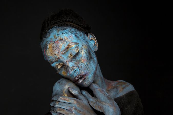 Portrait of woman with blue face pain against dark background