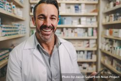 Smiling mature pharmacist with digital tablet standing by aisle in drug store 0yzRO5