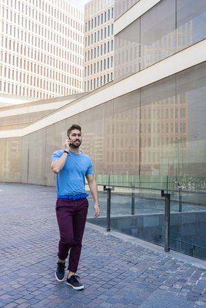 Portrait of modern businessman speaking on phone while walking outdoors