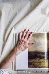 Older woman's hand on an open magazine 5qK8ab