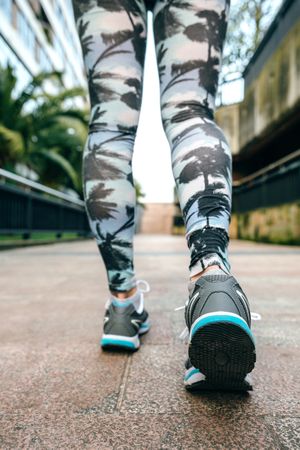 Legs of woman at start of workout wearing sneakers and tropical leggings