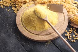 Pile of cornmeal on wooden plate with a wooden spoon and blank label