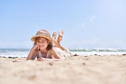 Happy boy leaning on hand while relaxing on seashore